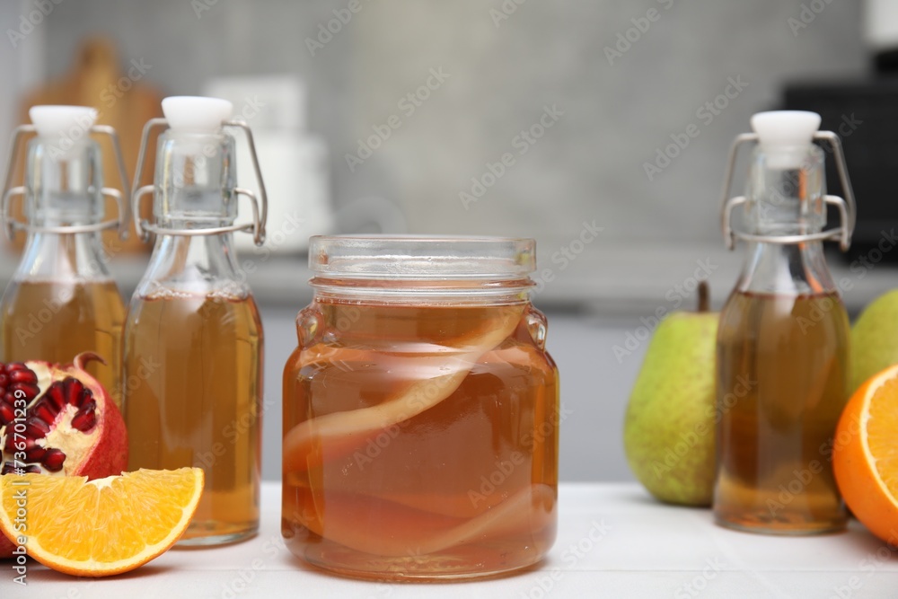 Homemade fermented kombucha and fresh fruits on white table in kitchen Homemade fermented kombucha and fresh fruits on white table in kitchen