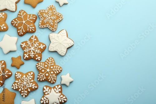 Tasty star shaped Christmas cookies with icing on light blue background  flat lay. Space for text