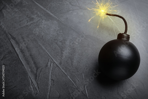 Old fashioned black bomb with lit fuse on grey table, top view. Space for text photo
