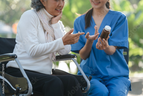 Compassionate Asian woman provides care to  elderly person in wheelchair outdoors. Engaging in physical therapy, happiness, encouraging positive environment for mature individuals with grey hair.
