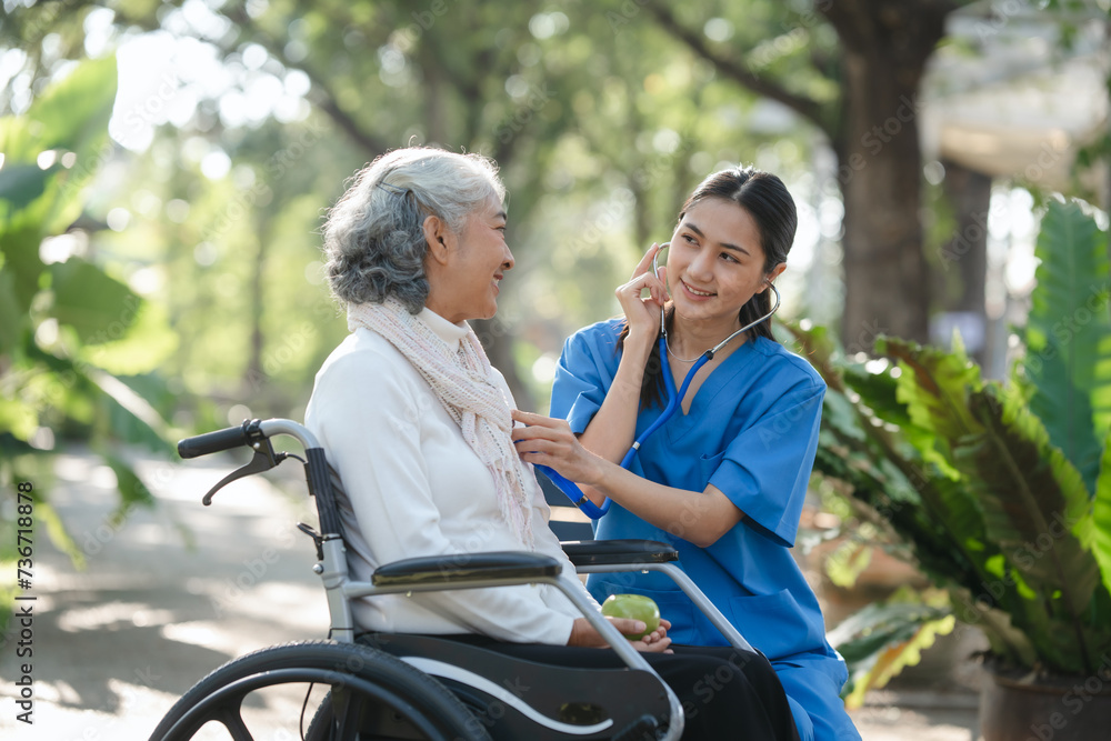 Compassionate Asian woman provides care to elderly person in wheelchair outdoors. Engaging in physical therapy, happiness, encouraging positive environment for mature individuals with grey hair. Compassionate Asian woman provides care to elderly person in wheelchair outdoors. Engaging in physical therapy, happiness, encouraging positive environment for mature individuals with grey hair.