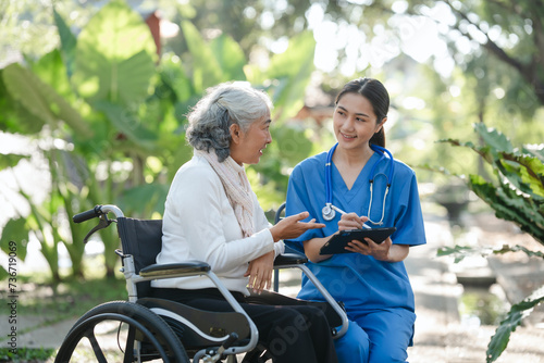 Compassionate Asian woman provides care to  elderly person in wheelchair outdoors. Engaging in physical therapy  happiness  encouraging positive environment for mature individuals with grey hair.