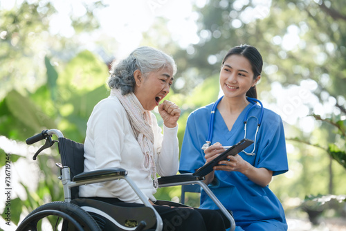 Compassionate Asian woman provides care to  elderly person in wheelchair outdoors. Engaging in physical therapy, happiness, encouraging positive environment for mature individuals with grey hair.