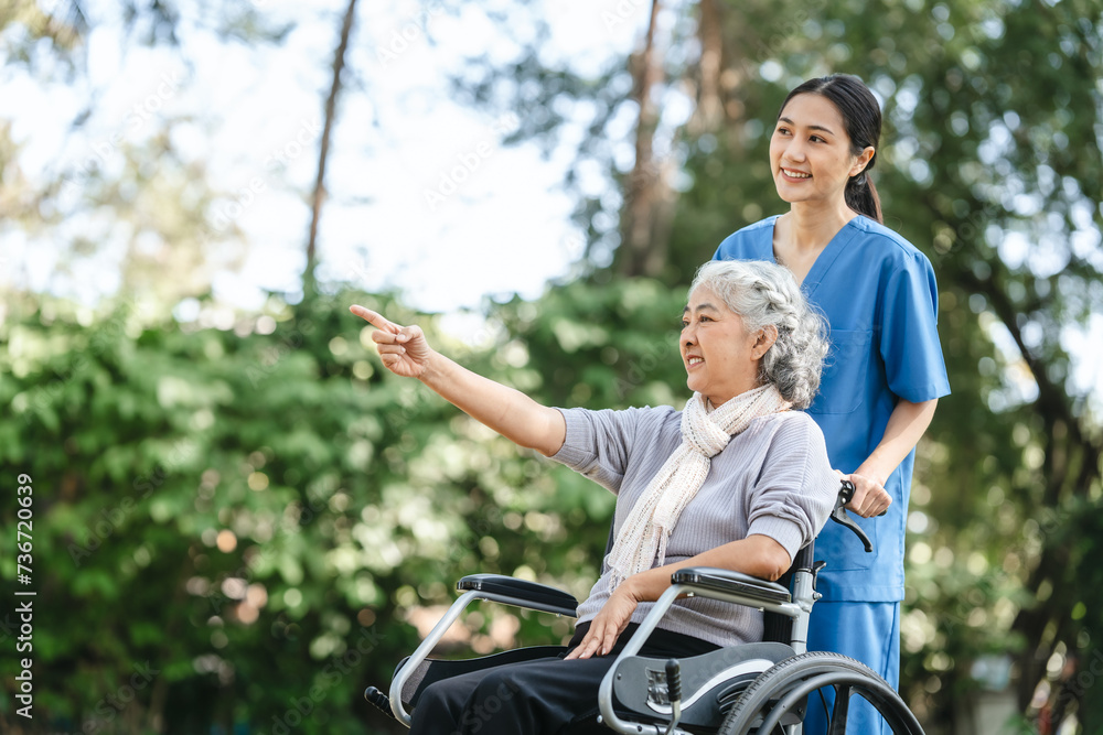 Compassionate Asian woman provides care to elderly person in wheelchair outdoors. Engaging in physical therapy, happiness, encouraging positive environment for mature individuals with grey hair. Compassionate Asian woman provides care to elderly person in wheelchair outdoors. Engaging in physical therapy, happiness, encouraging positive environment for mature individuals with grey hair.