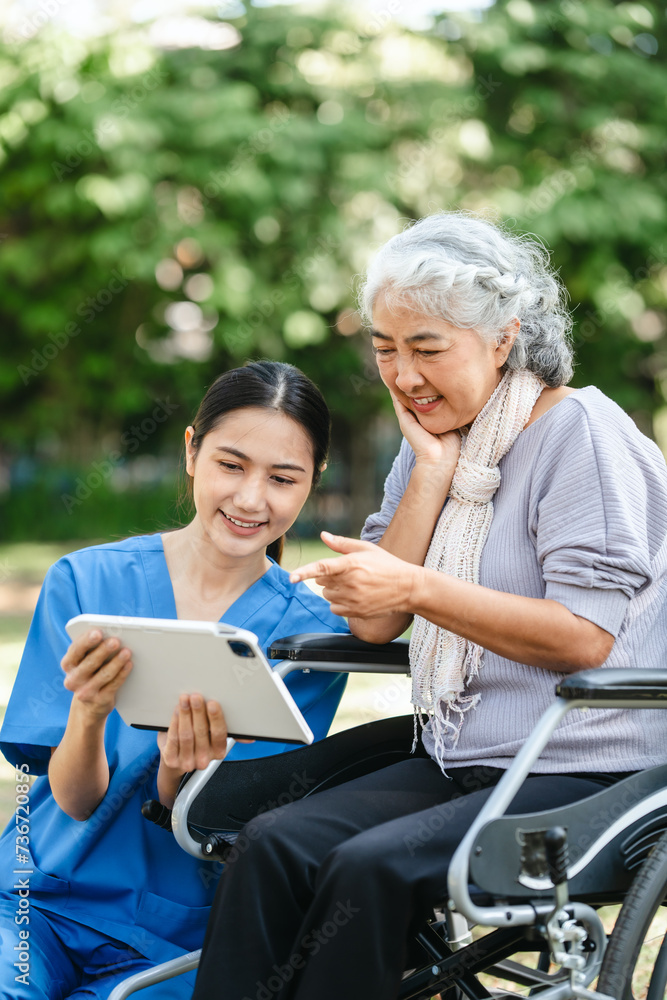 Compassionate Asian woman provides care to  elderly person in wheelchair outdoors. Engaging in physical therapy, happiness, encouraging positive environment for mature individuals with grey hair.