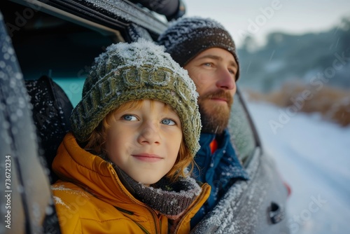 A father and son enjoy a snowy car ride, both warmly dressed and looking contemplative photo
