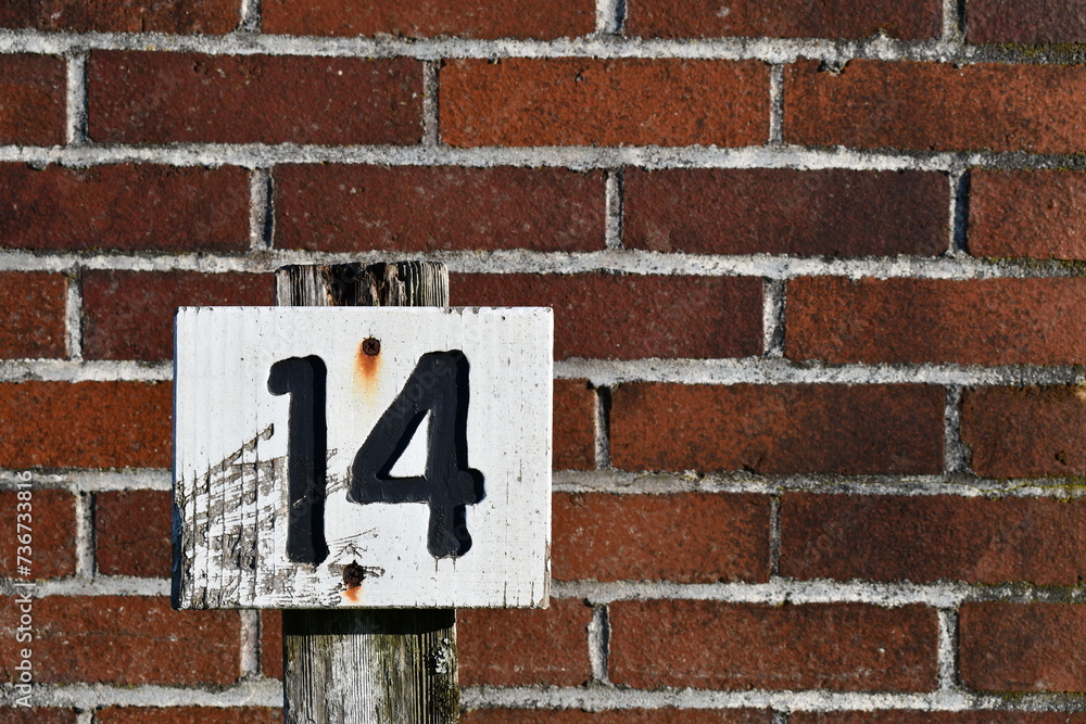 Number fourteen on white sign with red brick background. Number fourteen on white sign with red brick background.