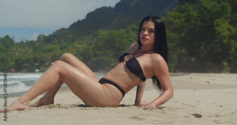 A Hispanic girl in a thong bikini, soaking up the sun on the white sandy beach onTrinidad's Caribbean island A Hispanic girl in a thong bikini, soaking up the sun on the white sandy beach onTrinidad's Caribbean island