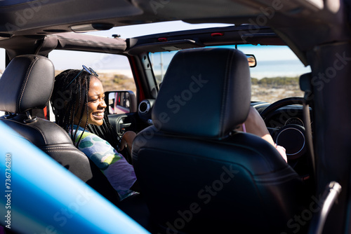 Young African American woman enjoys a car ride on a road trip photo