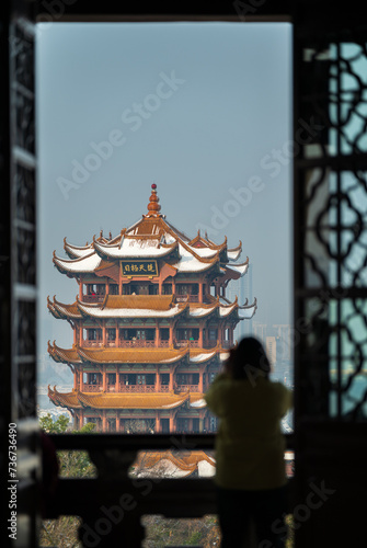 A tourist uses her mobile phone to take pictures of the Yellow Crane Tower in the snow.