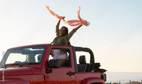 Young African American woman celebrates freedom on a coastal road trip photo
