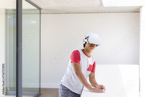 Teenage Asian boy explores virtual reality at home, with copy space