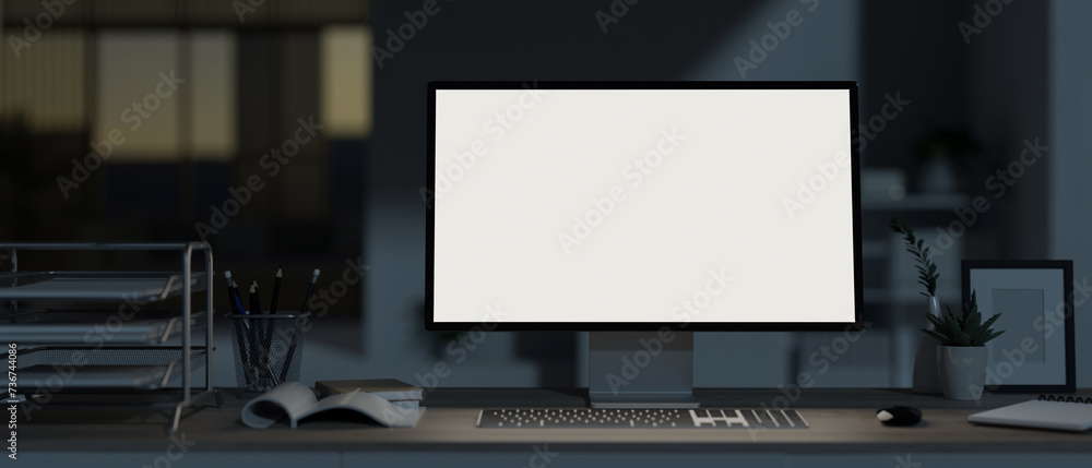 A modern, dark office at night with a white-screen computer mockup and office supplies on the desk. A modern, dark office at night with a white-screen computer mockup and office supplies on the desk.