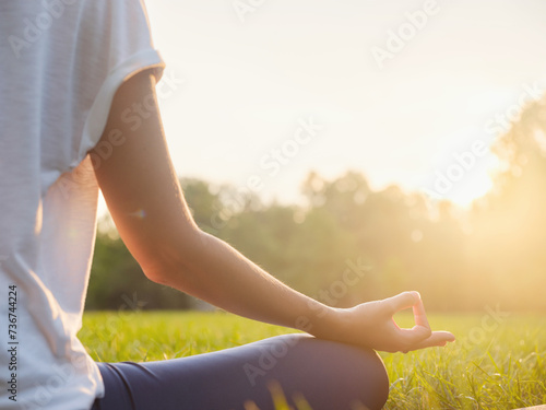 Obraz na plátně Young asian woman doing meditation in morning or evening at park, healthy woman relaxing and practicing yoga at city park