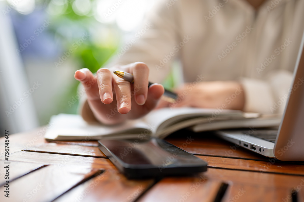Fototapeta premium A woman touching the screen of her smartphone while working remotely at a cafe.