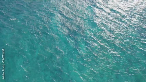 aqua turquoise water with the sun shining down into the crystal clear ocean water with rippling waves on the oceans surface and an ocassional white cap photo