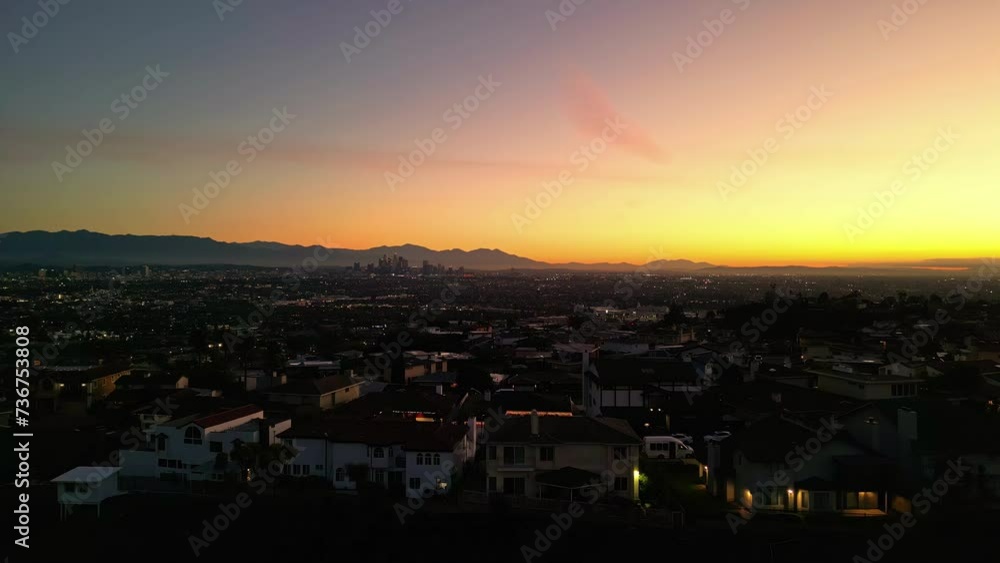 Aerial view backwards over a neighborhood with Los Angeles dusk skyline background Aerial view backwards over a neighborhood with Los Angeles dusk skyline background