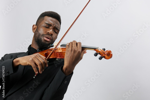 Man in suit playing violin against white background, African American musician performing classical music with instrument