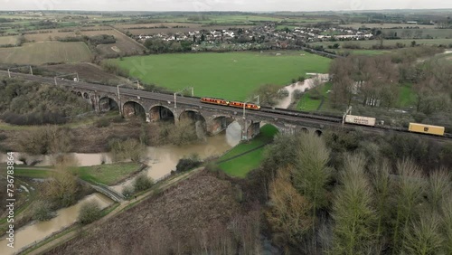 Aerial view of Haversham and Little Linford viaduct with freight and passenger trains crossing over it, Milton Keynes, Buckinghamshire, England. Flying right to left around the viaduct. photo