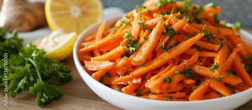 a bowl of carrots with parsley and lemon slices on a table . High quality