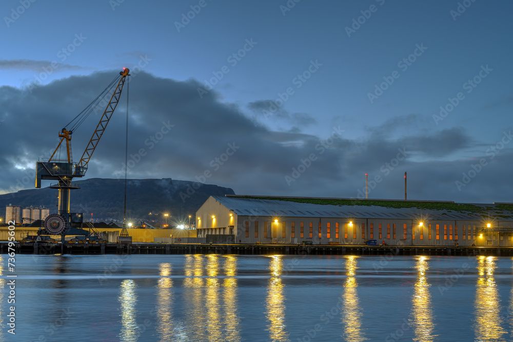 A loading crane and a storehouse in the port of Belfast at dusk