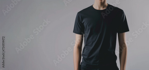 Model in a black T-shirt on a light background. Place for text.