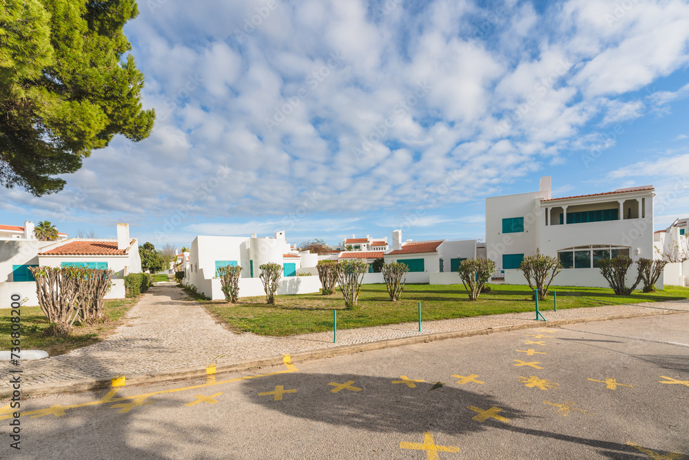 Naklejka premium Street in a vibrant tourist destination lined with pristine white condominiums under the cloudy sky.