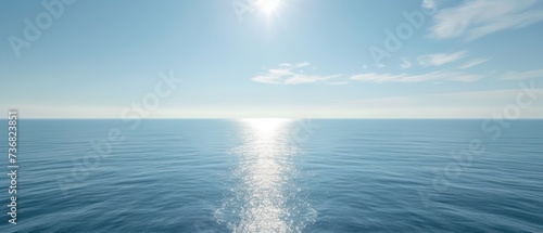 a large body of water with a bright sun in the middle of the sky and a line of clouds in the middle of the water.