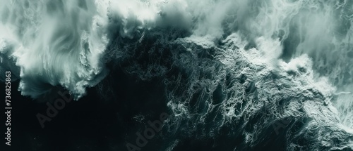 a black and white photo of a large wave in the ocean with white foam on the bottom of the wave.