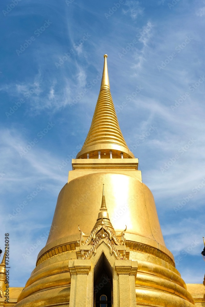 Naklejka premium Phra Si Rattana Chedi: a gold bell-shaped stupa at the Wat Phra Kaew (Temple of the Emerald Buddha) in Bangkok, housing relics of the Buddha from Sri Lanka, and covered in gold mosaic tiles