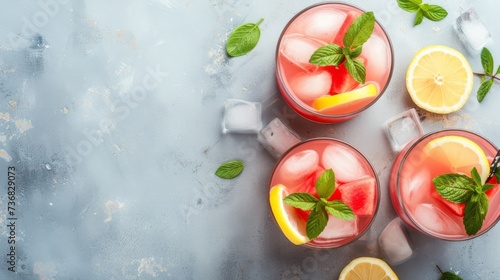 Fresh watermelon juice in glasses garnished with mint and lemon, surrounded by watermelon slices, ice, and lime. Great for summer, beverage, or health themes.