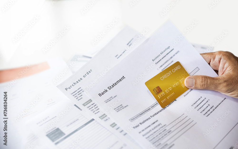 Close-up shot, hand of businessman holding credit card to checking purchase order and bank statement, A man start new business online and using a credit card to pay for order