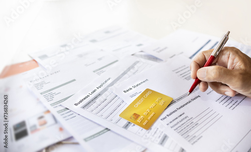 Close-up shot, hand of businessman holding pen checking bank statement to apply for a loan via credit card to start new business, Personal loan concept for start new business