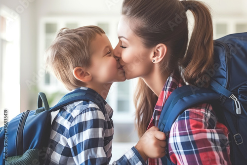 A mother kisses her young son on the cheek as they prepare for school, showcasing familial love. photo