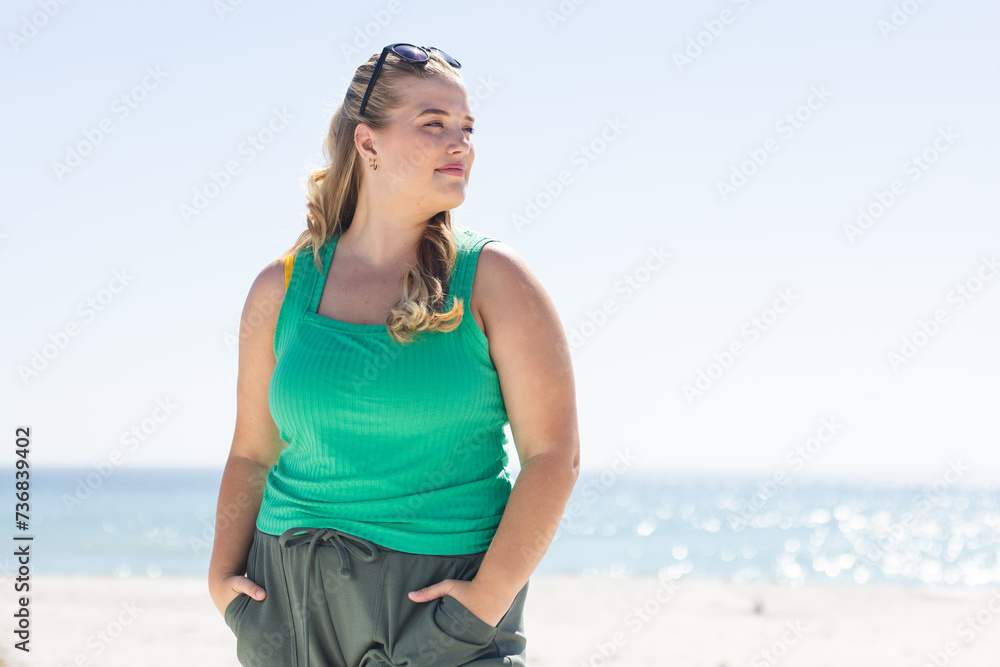 Fototapeta premium Young plus-size Caucasian woman stands confidently on the beach, with copy space
