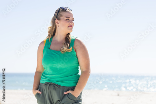 Young plus-size Caucasian woman stands confidently on the beach, with copy space
