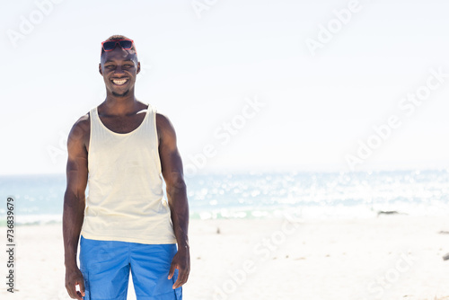 Young African American man enjoys a sunny beach day, with copy space unaltered