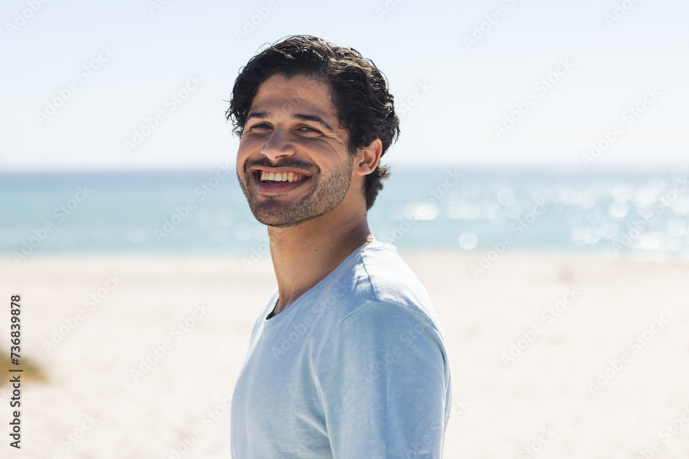 Fototapeta premium A young biracial man smiles brightly at the beach