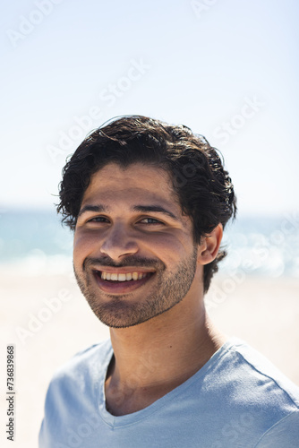 Young biracial man smiles brightly at the beach