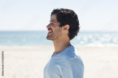 A young biracial man smiles brightly outdoors at the beach