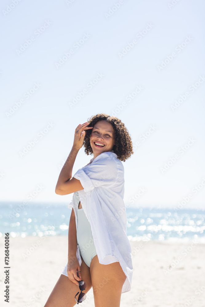 Young biracial woman enjoys a sunny beach day, with copy space unaltered Young biracial woman enjoys a sunny beach day, with copy space unaltered