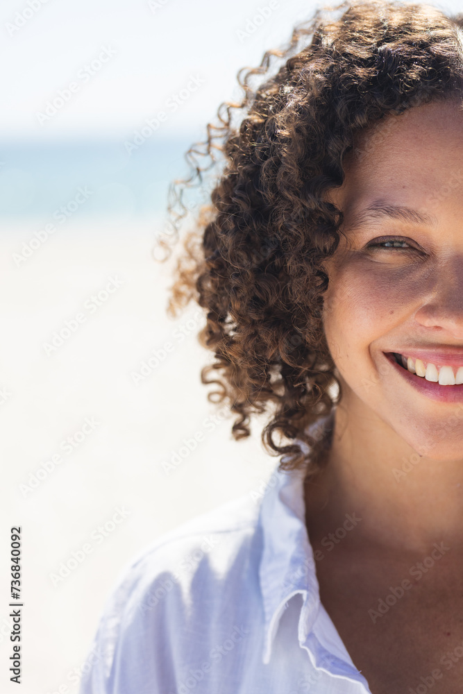 Fototapeta premium Young biracial woman smiles brightly at the beach