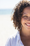 Young biracial woman smiles brightly at the beach
