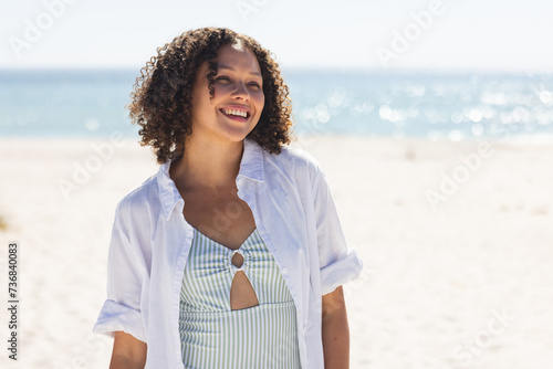 Young biracial woman enjoys a sunny beach day