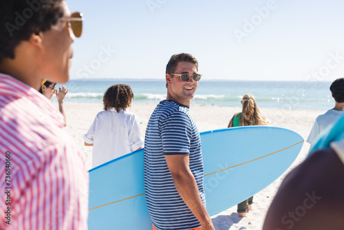 Young Caucasian man carries a surfboard on the beach
