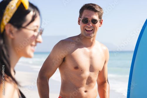 Young Caucasian man and biracial woman enjoy a sunny beach day