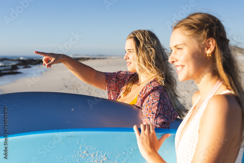 Two young Caucasian women enjoy a sunny beach day, with copy space