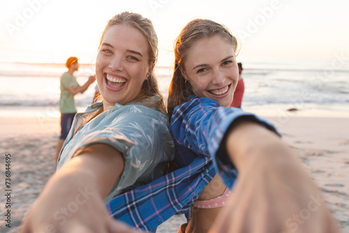 Two young Caucasian women share a joyful moment on the beach