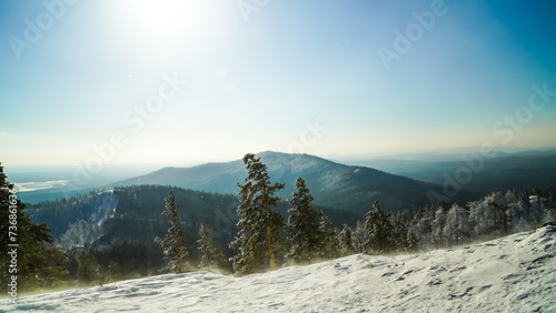 Beautiful panoramic view of the Ural ridge from the height of the mountain. Strong gusts of wind are blowing at the top of the mountain, carrying snow. 
