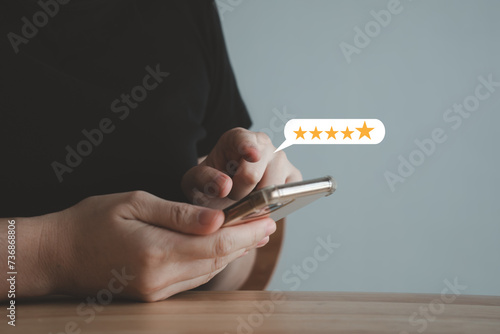 Customer using mobile smartphone for giving satisfaction score with five star excellent experience. Review the service with Best score. Customer Satisfaction survey and feedback rating concept.